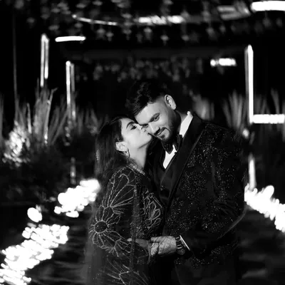 A timeless black and white portrait. The bride's gentle kiss on the groom's cheek, the soft lighting, and the classic monochrome finish create an image that is pure romance.