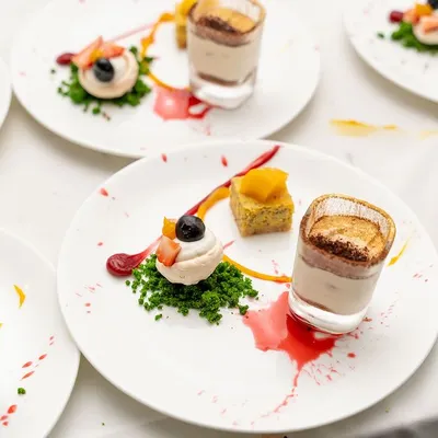 An exquisite plated dessert I created for a 50th birthday celebration. It features a trio of treats: a mini tiramisu, a delicate meringue with fruit, and a small cake, all artfully arranged.