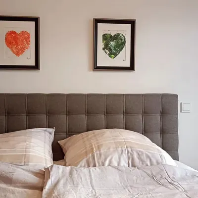 A pair of my textured heart paintings, one in red and one in green, hanging above a client's bed. They create a beautiful, balanced focal point, bringing colors of passion and nature into a calm, neutral space.
