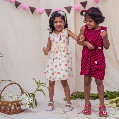 Double the fun, double the style! This video shows two happy girls in their comfortable and playful dresses, one in a quirky print and the other in a classic red and navy check.