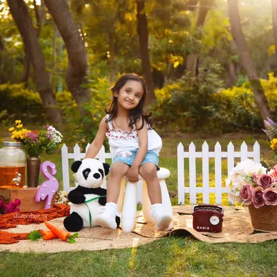A lovely outdoor portrait of a four-year-old girl enjoying a picnic in the park, surrounded by flowers and sunshine.