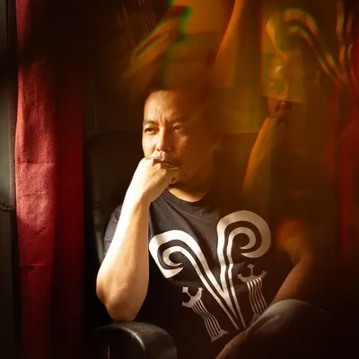 An atmospheric color portrait of tattoo artist Mo Naga in a moment of contemplation, with creative light flares adding to the mood. This image shows my approach to capturing the personality of professionals and artists.