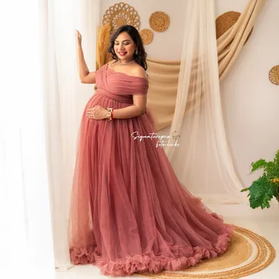 A beautiful solo portrait in a mauve gown, with the mother-to-be looking out a window, bathed in soft, natural light.