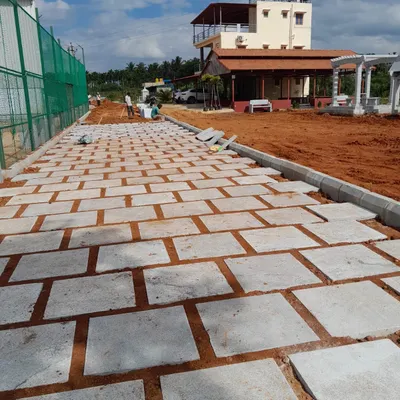 A long pathway under construction using large rectangular stone pavers. This image shows the foundational work involved in creating a durable and level walkway for a large property.