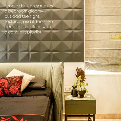 A minimalist bedroom with a dramatic grey 3D-paneled wall, a custom curved leather headboard, and bold red embroidered accents.