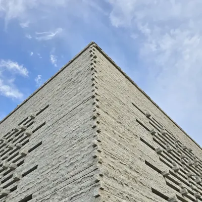 Our Tiruppur house is a symphony in stone. This upward shot shows the corner detail of the granite facade, where the texture of the stone meets the clean geometry of the sky.