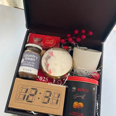 A luxurious New Year gift packed in a leatherette trunk. It includes an LED clock, a 2025 calendar, gourmet popcorn, coffee, and a scented candle to welcome the new year.