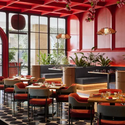 The dining area at Foo, where a bold red coffered ceiling and cherry blossoms create a dramatic, immersive atmosphere. The design balances traditional Asian color symbolism with a modern execution.
