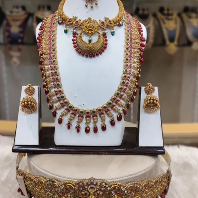 A classic kempu stone bridal set with a crescent-shaped pendant, paired with a matching long haram, jhumkas, and an intricate hip belt.