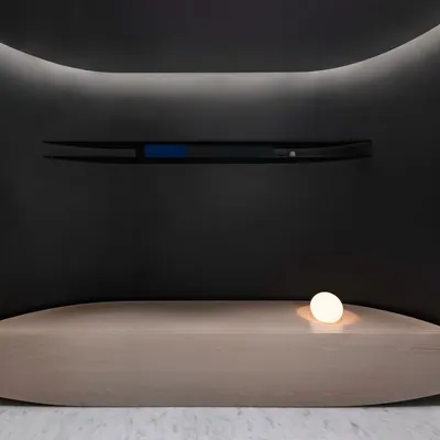 The entrance foyer introduces the project's theme with a doubly curved bench and a custom wall installation, set within a dark, intimate alcove.