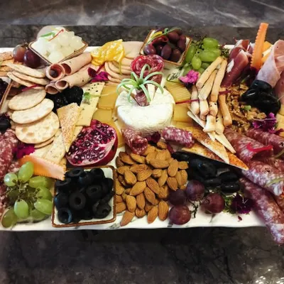 A lavish charcuterie and cheese grazing platter, overflowing with a variety of cured meats, artisanal cheeses, olives, nuts, and fresh and dried fruits. It's a statement piece for any corporate event.