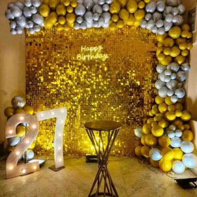 A dazzling gold sequin wall makes a statement at this 27th birthday party. Framed with gold and silver balloons and paired with marquee numbers, it creates a truly glamorous focal point.