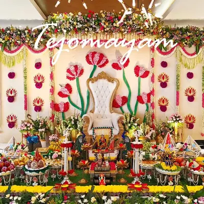 This aesthetic plate decoration for a baby shower features a grand floral backdrop with a throne, creating a royal setting for the mother-to-be. The entire stage is filled with meticulously arranged traditional offerings.