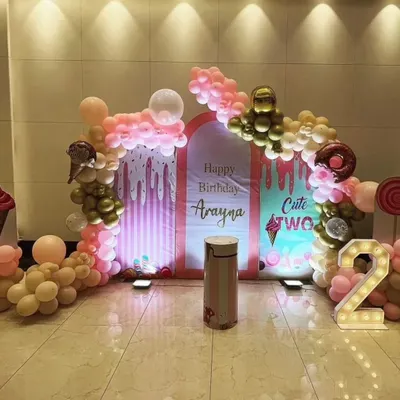A "Cute Two" ice cream theme for a second birthday. The setup includes pastel pink and gold balloons and backdrops with dripping ice cream patterns.