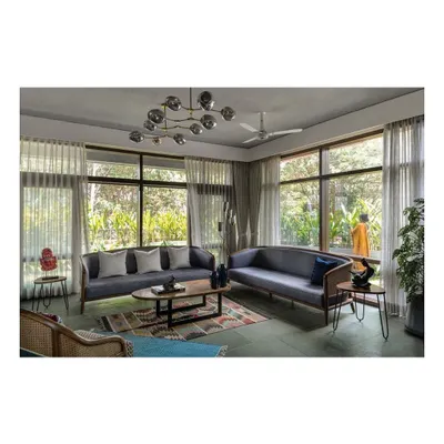 A living room set featuring two custom sofas with exposed wood frames and cane paneling. The design is complemented by a low-profile oval coffee table and hairpin leg side tables, creating a balanced composition of modern and natural materials.