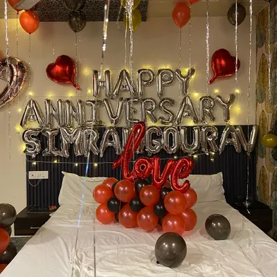 A close-up of a personalized anniversary decoration. I used silver foil balloons to spell out 'Happy Anniversary' along with the couple's names, with fairy lights behind them for a soft glow. The 'Love' balloon and other heart foils complete the theme.