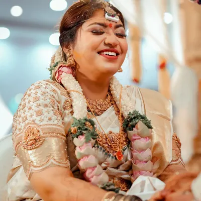 The pure joy of a wedding ceremony. This candid shot captures the bride's beautiful, uninhibited laughter during a traditional ritual.