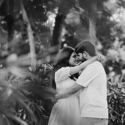 A beautiful black and white shot of a couple embracing in a garden. The monochrome tones and natural framing create a timeless and romantic feel.