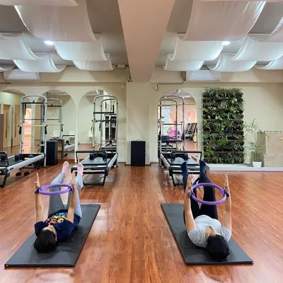 A mother and daughter enjoy a synchronized mat Pilates session using the magic circle. This wide shot captures the harmony and shared focus in our beautiful studio space.