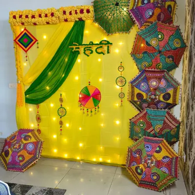 This is a complete Mehendi decoration I did for a client at their home. It features a bright yellow backdrop with green drapes, fairy lights, and a variety of embroidered Rajasthani umbrellas for a rich, traditional feel.