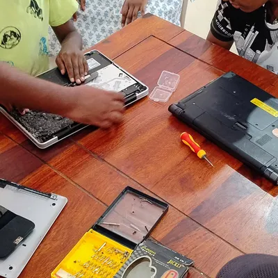 Teamwork makes the dream work. Here, kids collaborate to disassemble and inspect laptops during a summer camp workshop. They learn to identify different components and understand how they function together.