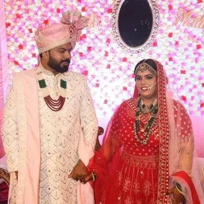 A classic groom look, featuring an off-white Lakhnavi sherwani with intricate embroidery, paired with a pink safa (turban) and dupatta to coordinate with the bride's attire.