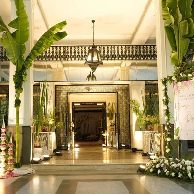 Creating an inviting entrance is key. For this wedding, I used large banana trees, traditional brass lamps, and mirror consoles, all highlighted with pink and white flowers to set a grand and welcoming tone.