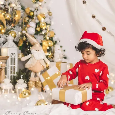 The magic of Christmas morning. This little one is captured in a moment of wonder, opening presents in a beautiful, festive setup.