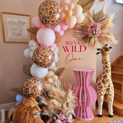A chic and modern take on the "Wild One" theme, combining giraffe-print balloons with soft pinks, pampas grass, and adorable stuffed animals for a stylish first birthday.