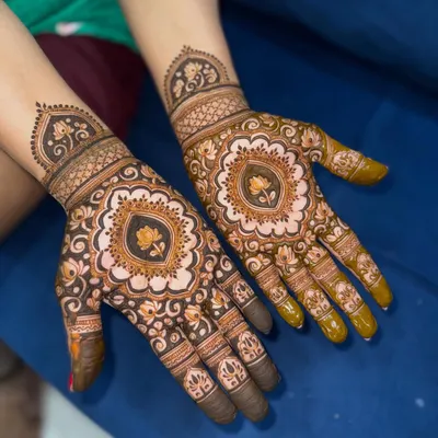 A beautiful Teej mehendi featuring a central lotus mandala. The design is symmetrical and filled with delicate details.