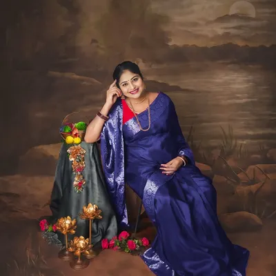 A solo portrait in a beautiful blue silk saree. The pose and the painted backdrop give this photo the feel of a classic piece of art.