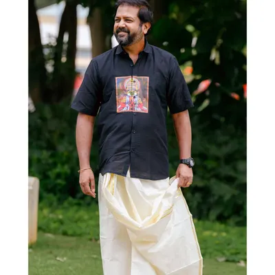 A candid-style shot of the model in a custom-printed black shirt and traditional mundu. This image captures a natural, relaxed moment, perfect for lifestyle branding.