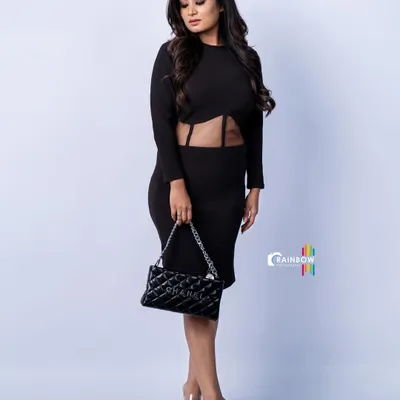 A full-length studio shot of a model in a sleek black dress. The clean white background and sharp lighting create a high-fashion look that emphasizes the model's pose and the outfit's silhouette.