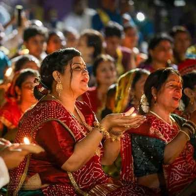 A devotee holds a lamp, her face filled with devotion during the Janmashtami celebration. The entire night is filled with singing, dancing, and remembering the playful spirit of Lord Krishna.