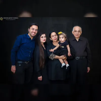 A precious multi-generational family portrait against a classic black backdrop. Capturing three generations together creates a priceless family heirloom.