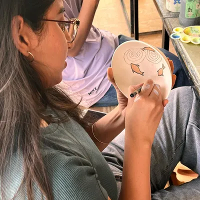 It's a very proud moment for me when my students enjoy the process and create beautiful pieces with so much love. This student is carefully painting a fish design on her handmade plate.