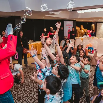 A bubble show entertainer mesmerizes a crowd of excited children as they reach for the floating bubbles. This show brings a sense of wonder and delight to any party.