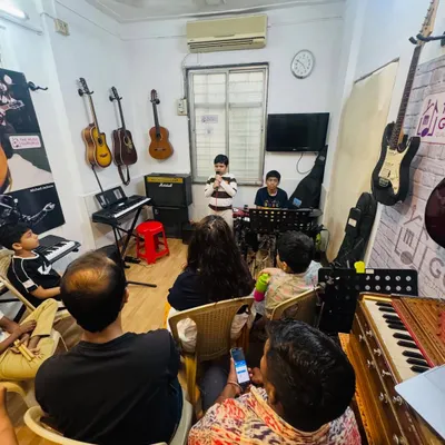 A wide shot of our 'Musical Saturday' jam session. An audience of parents and fellow students watches attentively as a young performer takes the stage, creating a real concert atmosphere.