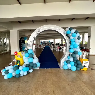 Welcome to the race! This circular entrance arch, decorated with a road pattern and balloon garlands, creates an exciting entryway for a Dinky Cars-themed birthday party.