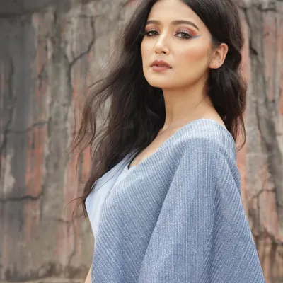 A designer shoot against a rustic, architectural backdrop. I styled this blue jumpsuit with a unique silhouette to create a strong contrast with the textured, earthy tones of the location.