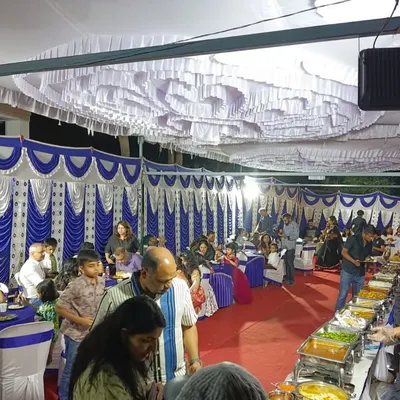 A large-scale housewarming party with a full tent setup. Our team seamlessly manages the buffet line, serving a large number of guests in an outdoor setting.
