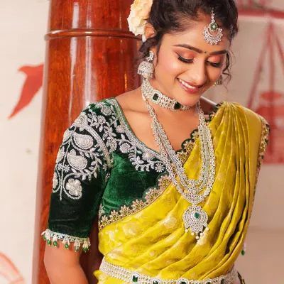 Elevate your saree with this luxurious dark green velvet blouse. It features heavy silver embroidery on the sleeves, available to rent separately for your special event.