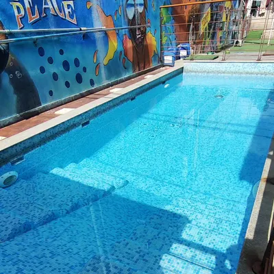 A view of our sparkling clean, tiled pool with its easy-entry steps. The "TEACH PEACE" mural in the background reflects the calm and happy vibe we cultivate.