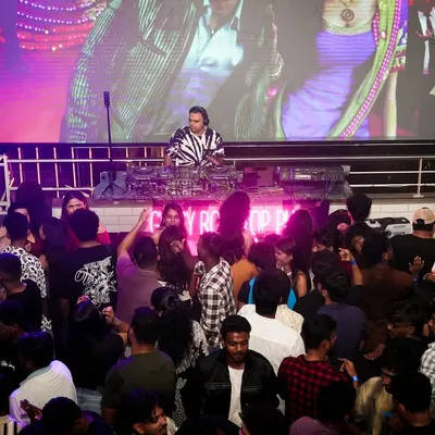 A wide shot showing the full scale of my VJ setup. With me at the decks and a massive LED screen behind me playing synced visuals, the entire venue is transformed into a dynamic audio-visual spectacle.