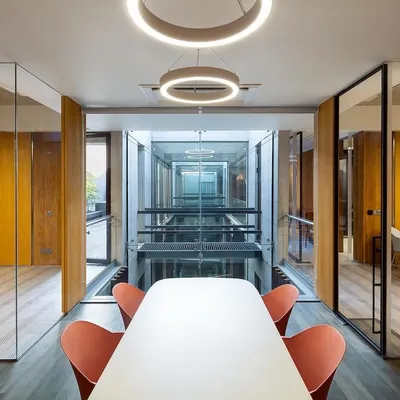 The interior planning of the Laxcon office creates visual porosity. A conference room is positioned to overlook the central triple-height void, maintaining a feeling of connection between different functional zones within the corporate building.