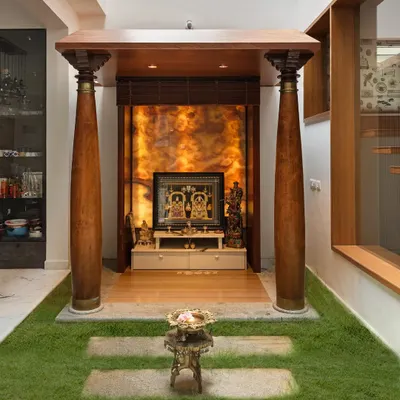 A frontal view of the pooja space in the Twin Courtyard House. The mandap is framed by two large, reclaimed wooden pillars, and the backlit onyx panel creates a divine glow.