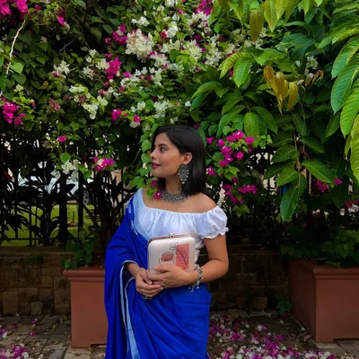 A perfect example of modern ethnic style. Here, my abstract face art clutch is paired with a beautiful blue saree and a statement oxidized silver necklace, showing how my accessories can complete any look.