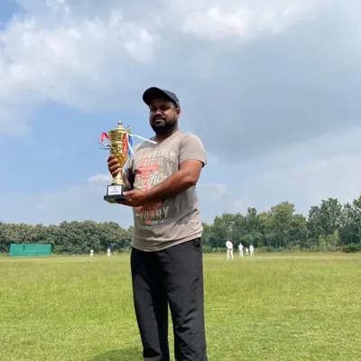 A proud coach holds the championship trophy after our U12 team's victory. Our coaches' dedication is a huge part of our players' success.