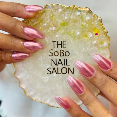 A stunning example of a full chrome manicure. These long, almond-shaped nails are coated in a vibrant pink chrome powder, giving them a liquid metal look that is incredibly reflective and glamorous.