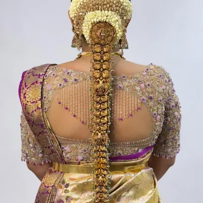 A showcase of an intricate back design. This blouse features a sheer back with delicate beadwork forming a beautiful pattern, finished with hanging tassels for a touch of glamour. It’s designed to make a statement.